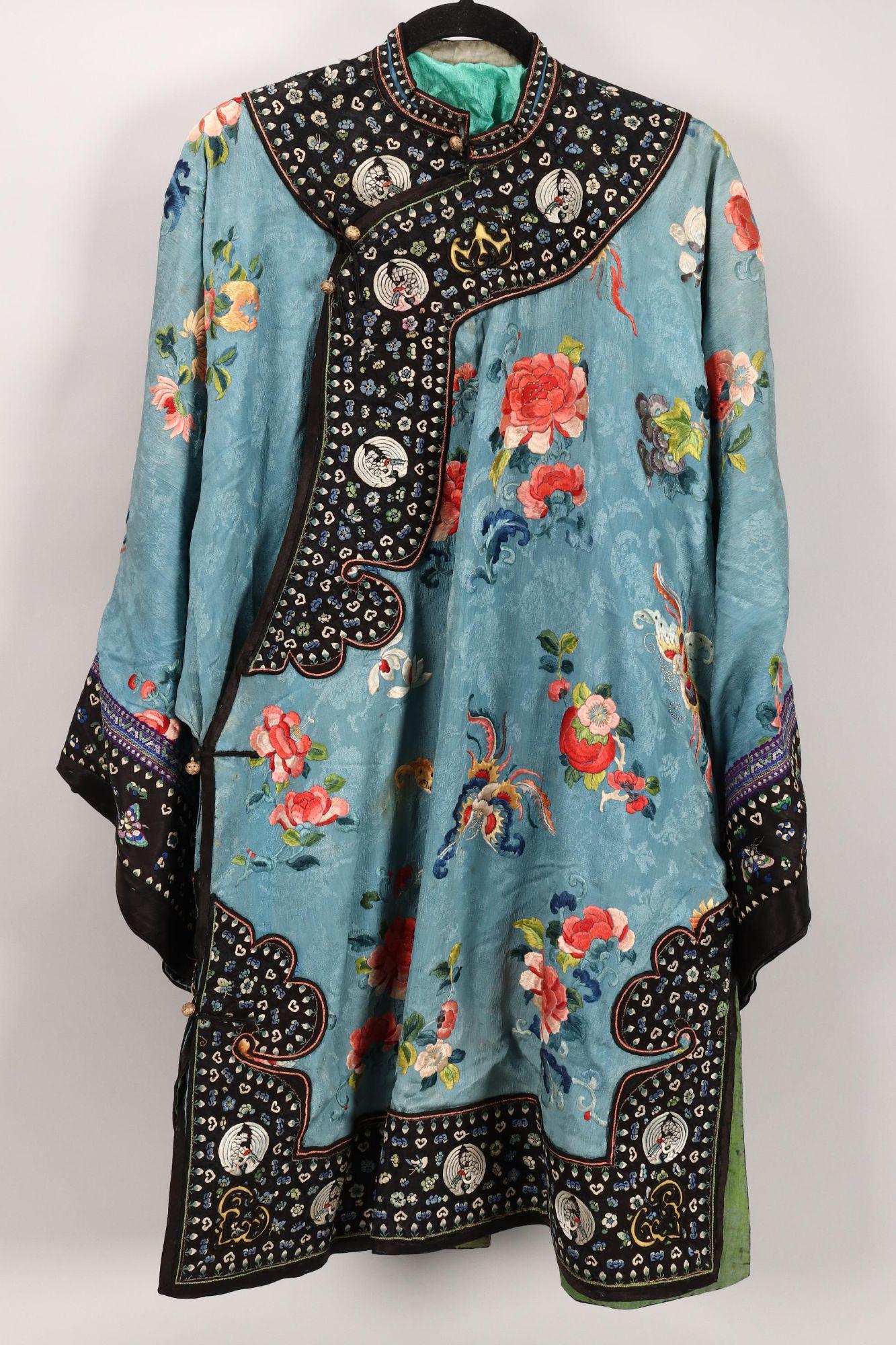 Chinese Embroidered Pale Blue Long Jacket,: embroidered with peonies, butterflies and fruit, in tones of pink, blue, yellow and green on a blue silk ground, with black satin borders embroidered with crane roundels, ruyi head and floral motifs, 