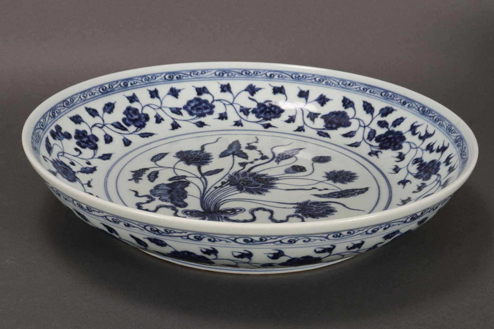 Chinese Blue and White Porcelain Charger,: probably Ming dynasty, of deep circular form, the interior decorated with central roundel of lotus flowers and seed pods, the exterior similarly decorated above a key fret border, with wax seal mark t