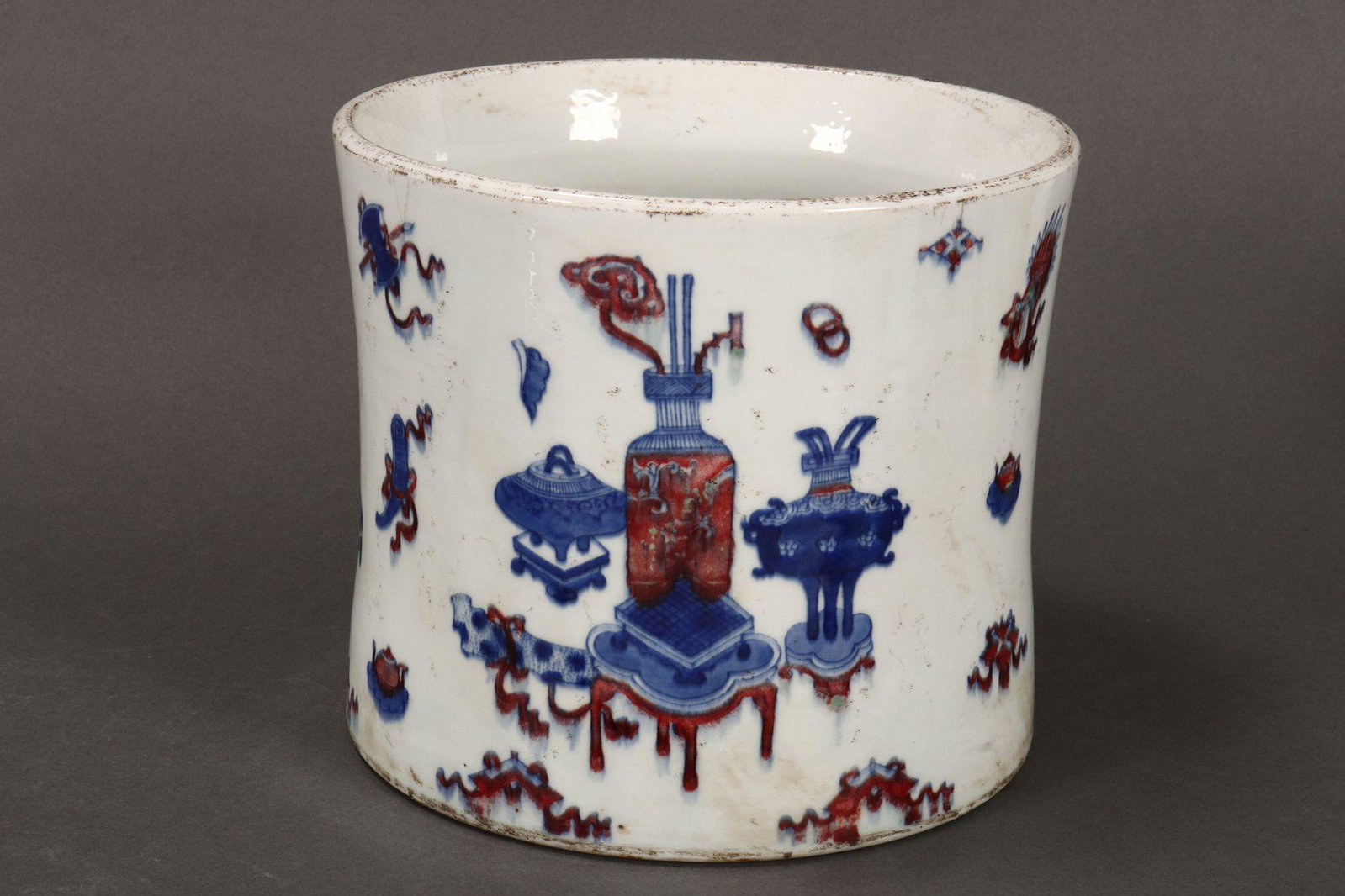 Chinese Porcelain Brush Pot,: of slightly waisted cylindrical form, the exterior decorated with vases, censers and Buddhist motifs, in tones of blue and red on a white ground, six character mark to base, height 17cm and diameter 1