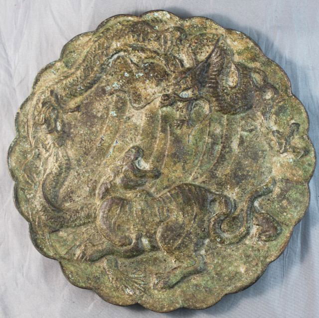 Chinese Bronze Mirror,: of shaped scalloped form, decorated a tiger and dragon, rubbed incised characters to back, d 23cm