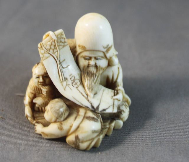 Two Carved Ivory Figures,: one in the form of an old man with frog, the other with man and two children, (2)
