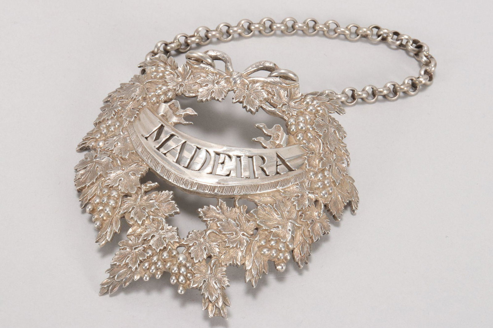 Large George III Sterling Silver Wine Label,: hallmarked London, 1806, B.S (Benjamin Smith II), in opulent wreath design with finely cast depictions of vine leaves and grapes encircling a central banner with pierced 'Madeira' label, total weight 
