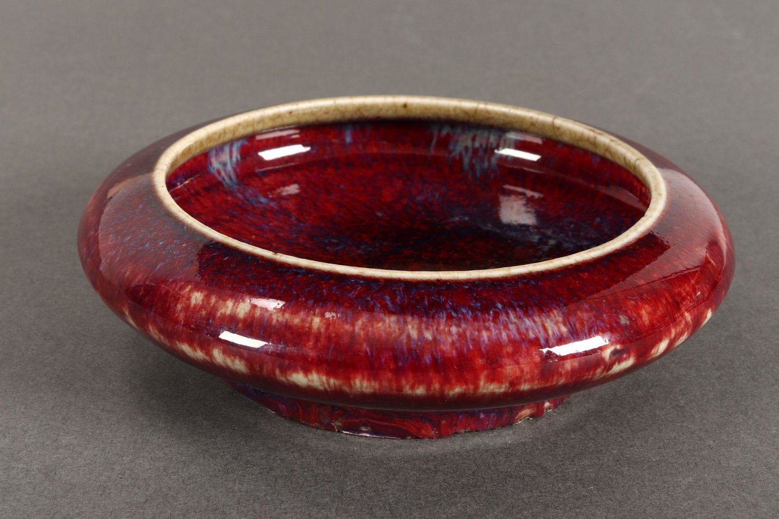 Chinese Qing Dynasty Sang de Beouf Brush Washer,: of squat circular form, in a red with mottled blue tones, on circular unglazed foot, diameter12.5cm