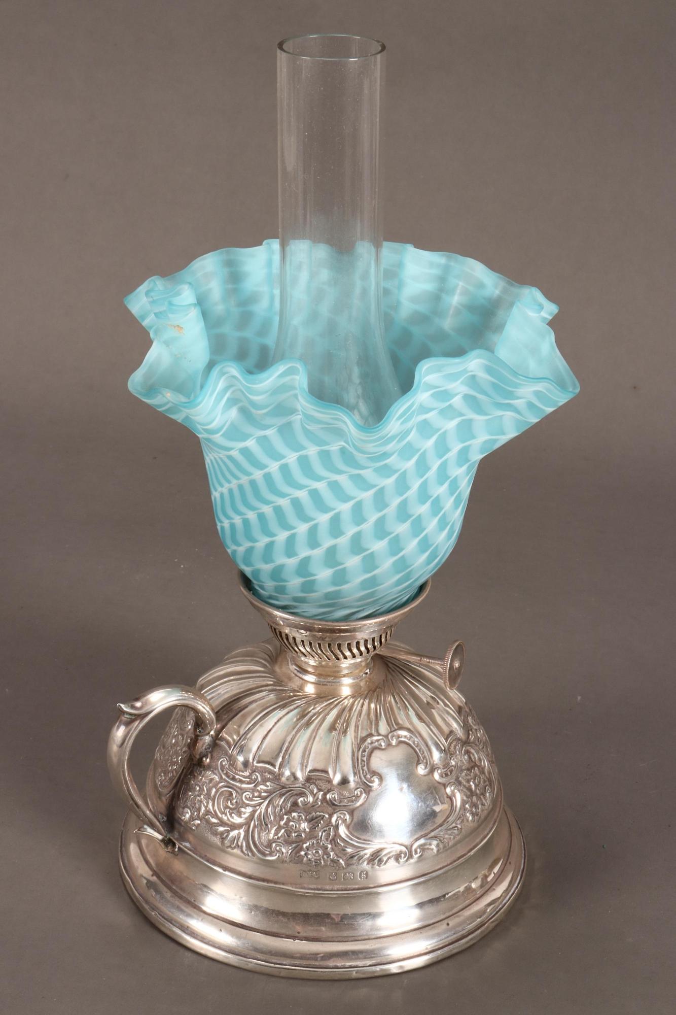 Edwardian Sterling Silver Oil Lamp,: hallmarked Birmingham, 1906, J&C (Jones & Crompton), the domed sterling silver base with loop handle and embossed with acanthus, c-scroll cartouches and floral motifs, with a blue glass shade with a f
