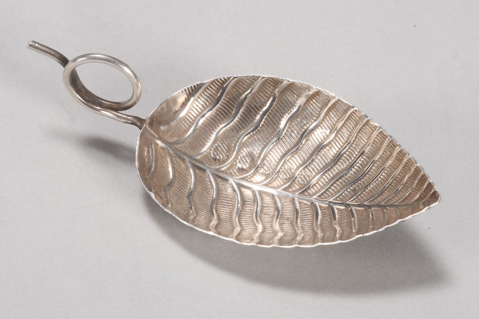 George III Sterling Silver Caddy Spoon,: hallmarked Birmingham, 1801, IT (John Taylor), the bowl of leaf form with textured finish and pronounced midrib and vein skeleton, with tendril loop handle, total weight 6.7gm, length 7.2cm