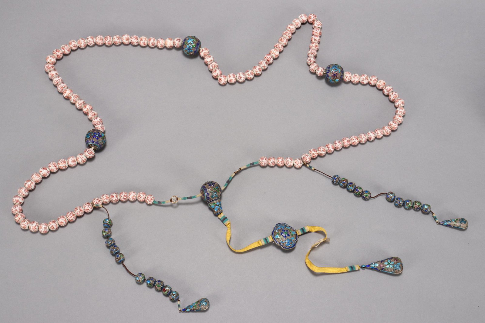 Late Qing Dynasty Mandarin Court Necklace,: composed of 108 porcelain beads painted with Shou symbols in orange on white, set with four larger filigree and enamel spheres decorated with bats and flowers, accented with twenty smaller spheres and