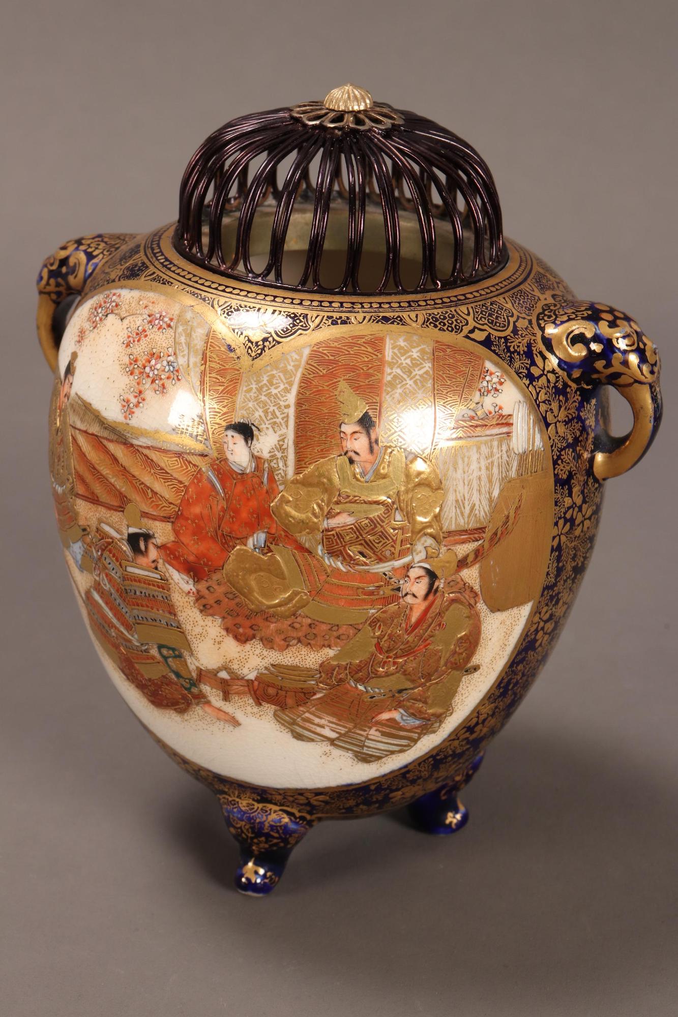 Japanese Meiji Period Satsuma Censer,: of bulbous form with twin mask handles, beautifully decorated to each side with a shaped reserve depicting court figures in an interior setting, on a cobalt ground with repeating foliate motifs, Kozan