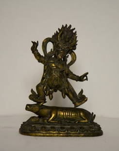 Nepalese 17th Century Gilt Bronze Figure of Yama: Dharmaraja,the wrathful deity his hair flaming , standing in alidhasana, standing two square on a recumbent figure of a buffalo, resting on a lone lotus throne, h 25.8cm Prov: Estate of the Late A.W D