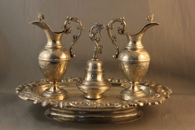 19th Century Spanish Silver Cruet Set, Barcelona ,: fitted with two amphora like oil decanters and a central bell , on a stepped tray , with pressed foliate decoration to rim , resting on a socle base l 23cm