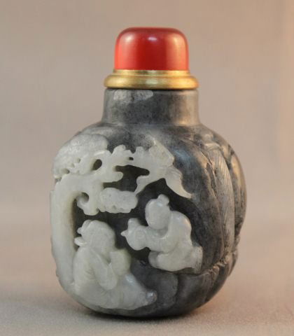 Chinese Black and White Jade Snuff Bottle and: Stopper, one side carved with two figures the other carved with landscape, with a clear red stopper, h 8.5cm