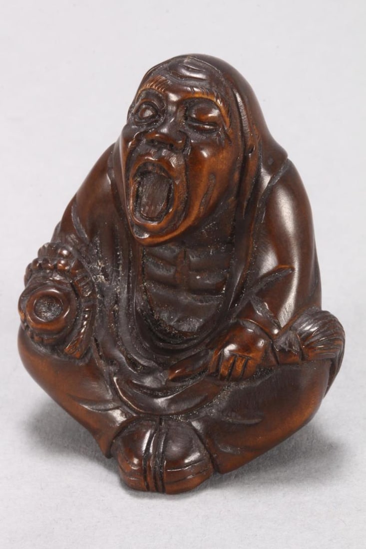 Japanese Carved Wooden Netsuke,: depicting a seated and yawning Daruma, signed to base, height 5.5cm