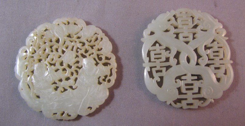 Two Chinese White/Pale Green Jade Discs,: one carved and pierced with two figures, the other carved with symbols of longevity, (2) Provenance: Estate of Late L.F Newman (China 1921-1942) The Chinese Salt Department