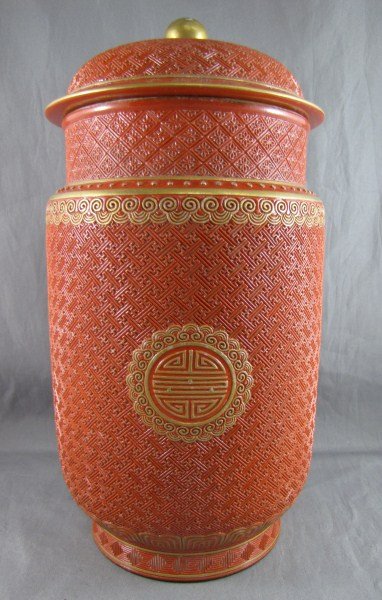 Chinese Porcelain Cylindrical Covered Jar,: simulating cinnabar lacquer, finely engraved with repeat cell patterns, Shou emblems and lappets and gilded on the edges. The interior and base enamelled black, Qialong four character mark in gold, wi