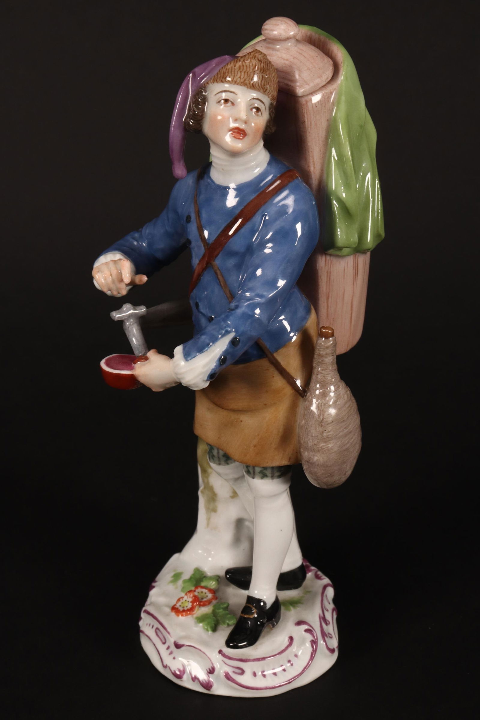 18th Century Meissen 'Cris de Paris' Porcelain: Figure of a Liquorice Water Seller, c.1760-65, modelled by Peter Reinicke after a drawing by Christophe Huet from 1753, depicted wearing a blue tunic with brown apron, the tank on his back with cover,