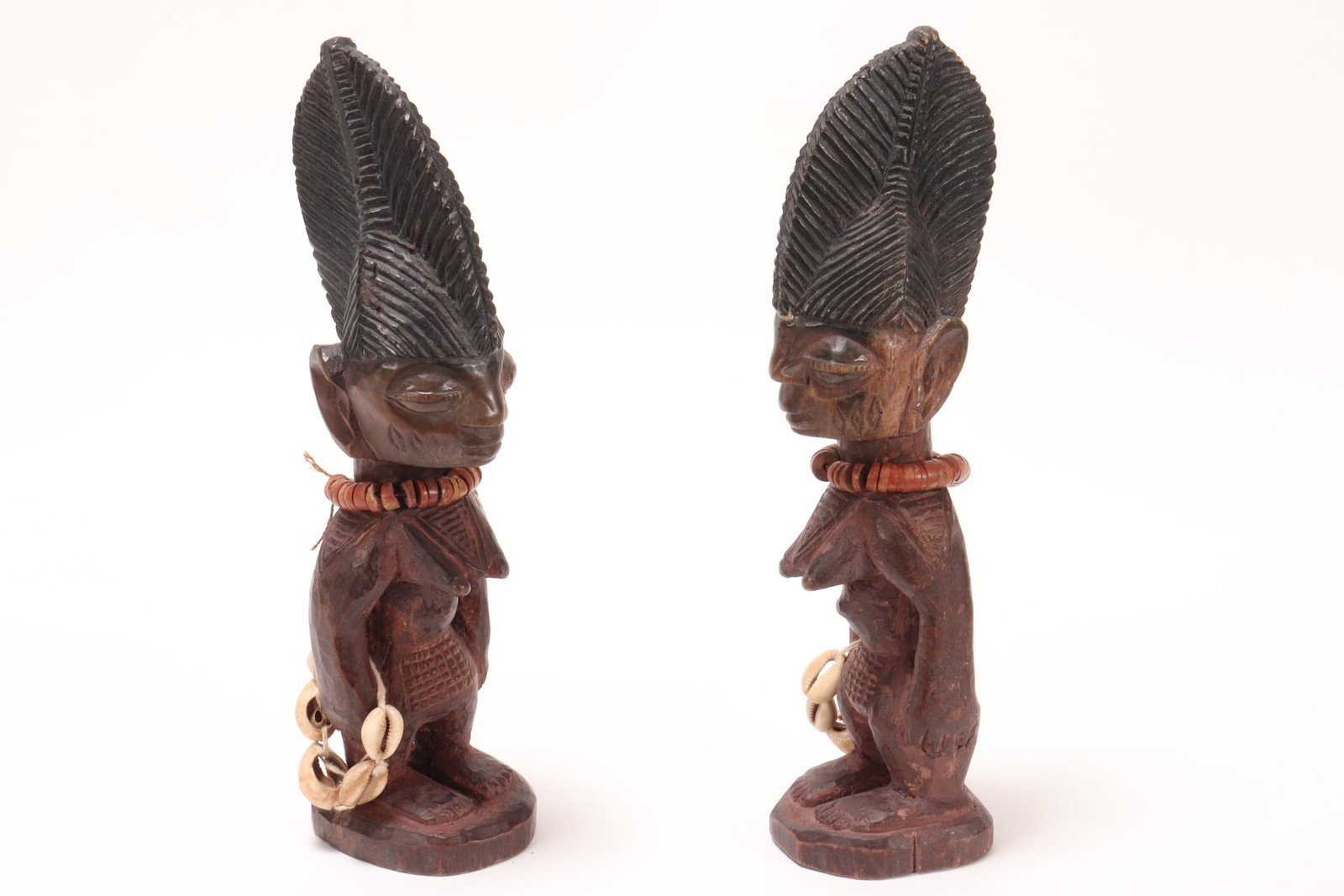 Pair of Yoruba Ibeji Twin Figures,: with carved headdress, depicted standing and decorated with beaded necklaces and shells, height 30cm (2)