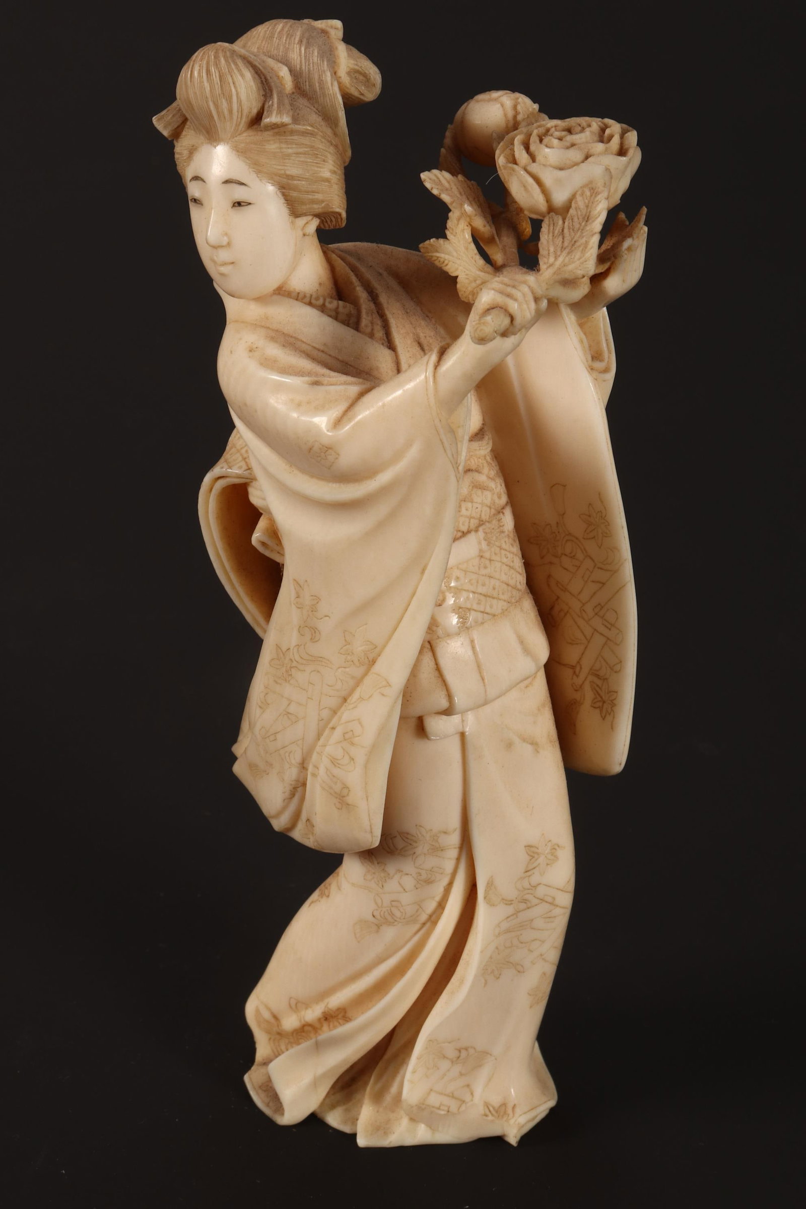 Japanese Meiji Period Okimono,: carved in the form of a geisha holding a floral branch, signed verso, height 13.5cm Please Note: This lot can only be shipped WITHIN Australia.