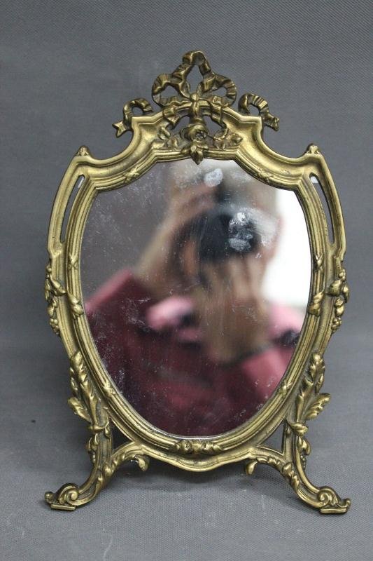 Late 19th Century Brass Table Mirror,: of shield form, with a riboned crest rail, surrounded by acanthus motifs on two feet with back support, h 34cm
