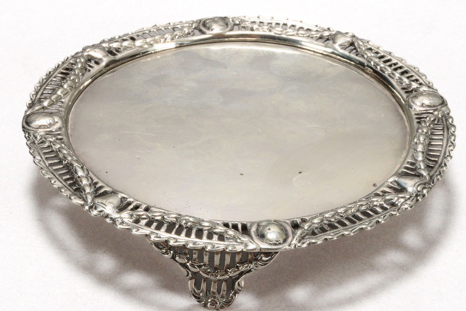 Late Victorian Sterling Silver Card Tray,: hallmarked London, 1898, CS//H (Charles Stuart Harris), of circular form with a pierced rim, decorated with an alternating pattern of urns, foliage and portraits, standing on three pierced feet, with