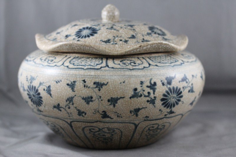 Vietnamese 14th Century, Crackle Glaze Blue: and White Jar and Cover, of squat baluster form, with a scalloped lip, decorated with bands of scrolling floral motifs, d 20cm