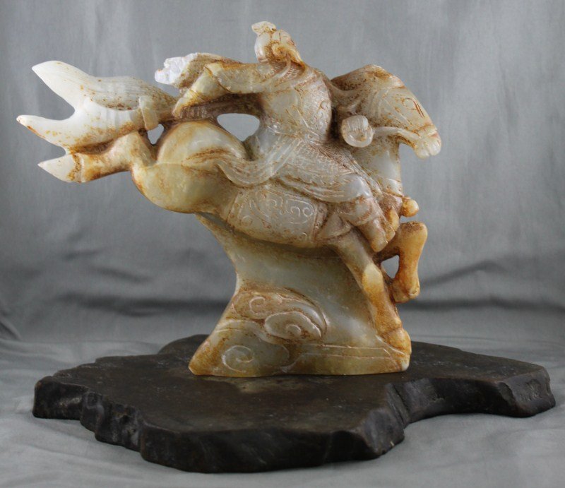 Chinese Carved Jade Figure Group,: in the form of a warrior brandishing a weapon riding a leaping horse, in tones of white, grey and russet, on stand, a/f, 21.5cm x 18cm Provenance: Jimmy Zhu Collection