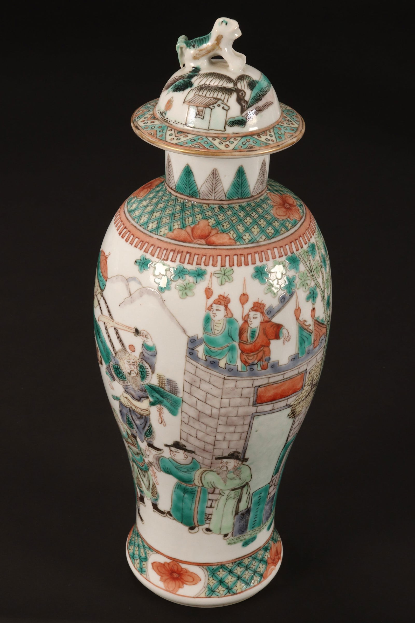 Chinese Famille Vert Porcelain Vase and Cover,: of baluster form, set with fo dog finial, above a continuous scene of an emperor on horseback with warriors and attendants outside of a villages gates, set with geometric and flower borders, in tones