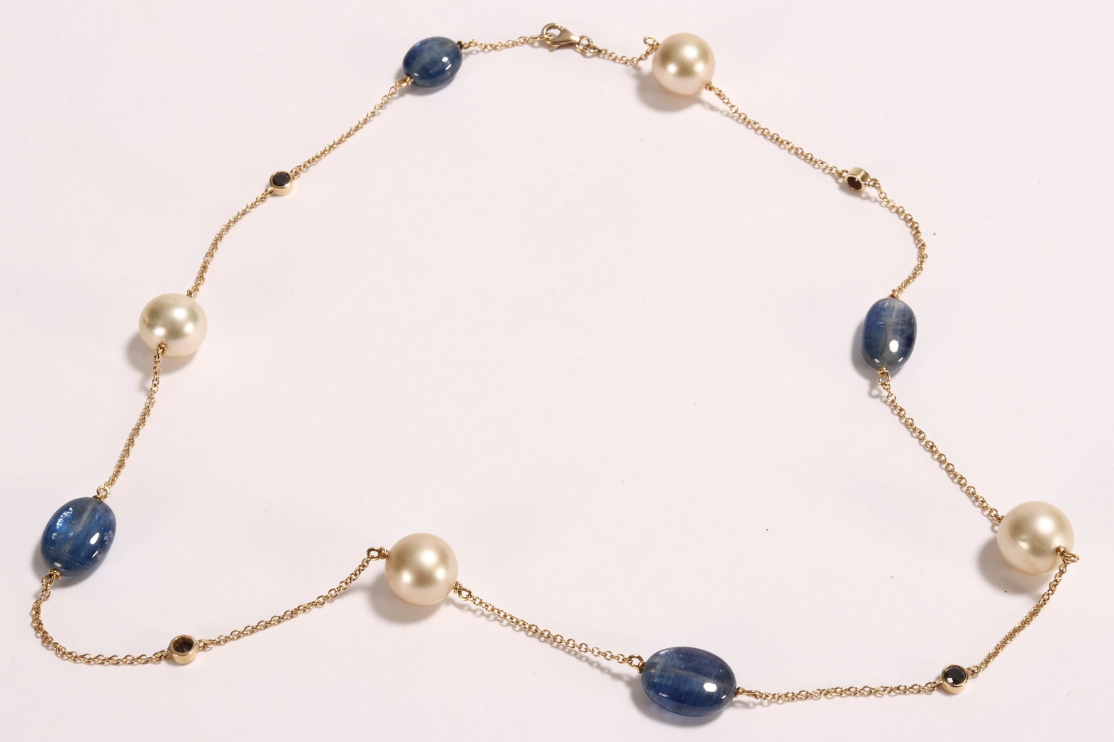 Lovely 9ct Gold Pearl and Sapphire Necklace,: stamped 375 to clasp, the fine link yellow gold chain suspending four champagne coloured spherical cultured pearls of approx. 11.5mm diameter each, four oval cabochon cut blue sapphires of varying siz