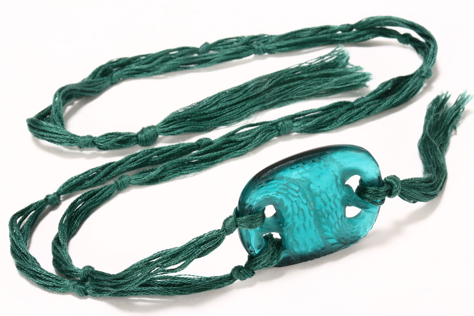 Rene Lalique 'Serpents' Pendant, c.1920,: model #1651, in sea-green glass, engraved verso 'R.Lalique', moulded to the front with two coiled serpents with exposed fangs, 44mm x 37mm, suspended on a green braided strap with tassels