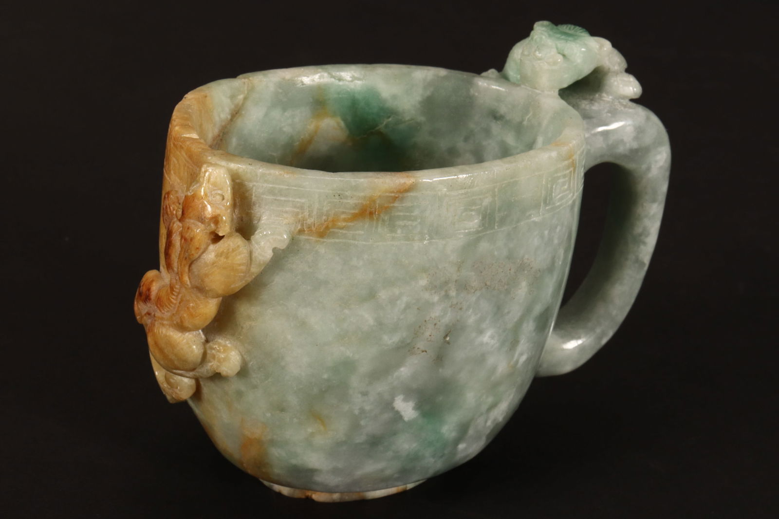 Chinese Late Qing Dynasty Jadeite Libation Cup,: of oval form, the handle and body displaying chilong, with Greek key border, in rich tones of emerald green, white and brown, age wear, 7cm x 9cm