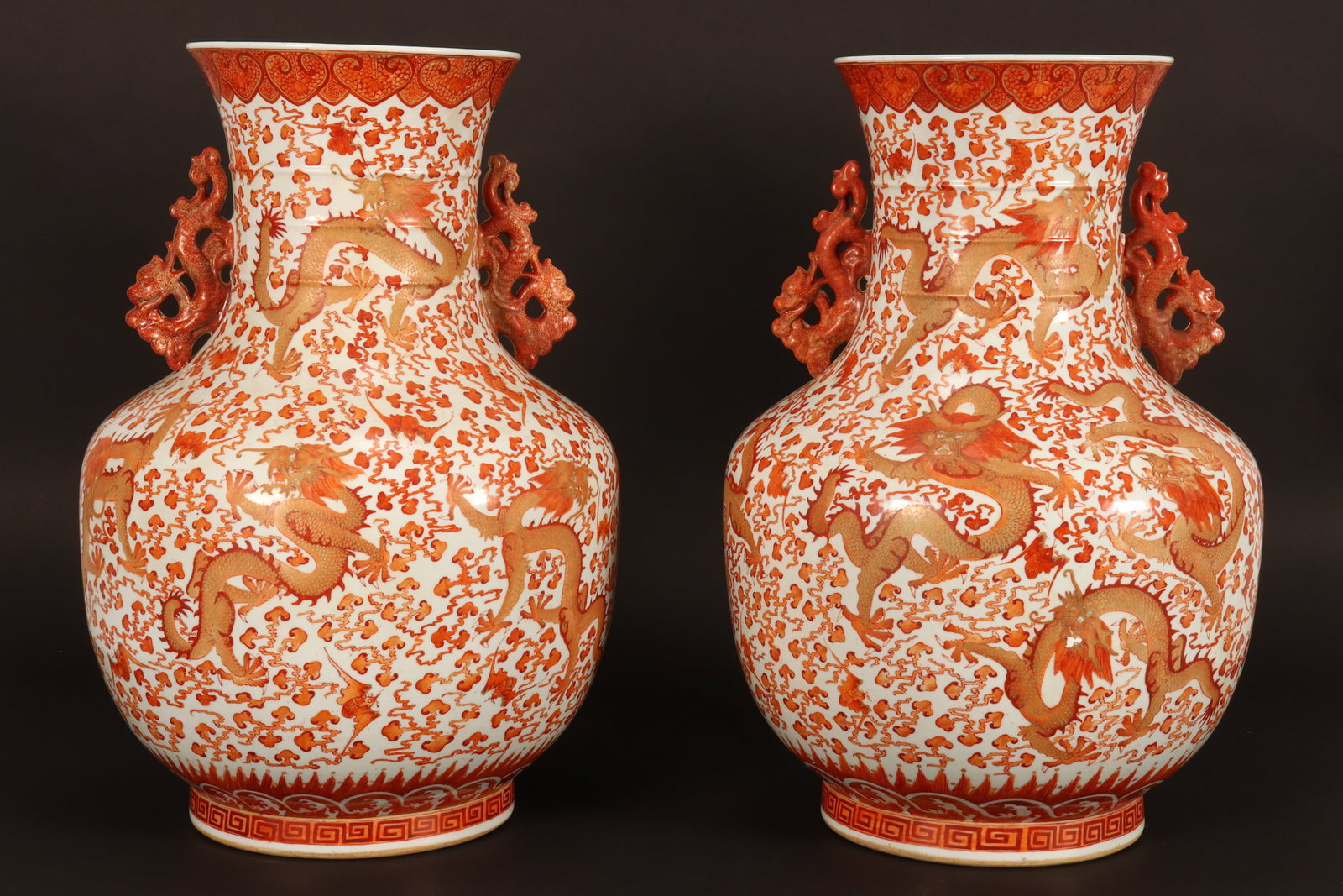 Pair of Chinese Porcelain Floor Vases,: of baluster form with twin pierced dragon handles, decorated with a continuous scene of multiple dragons surrounded by bats and stylised clouds, accented with Greek key and ruyi head borders, in tones