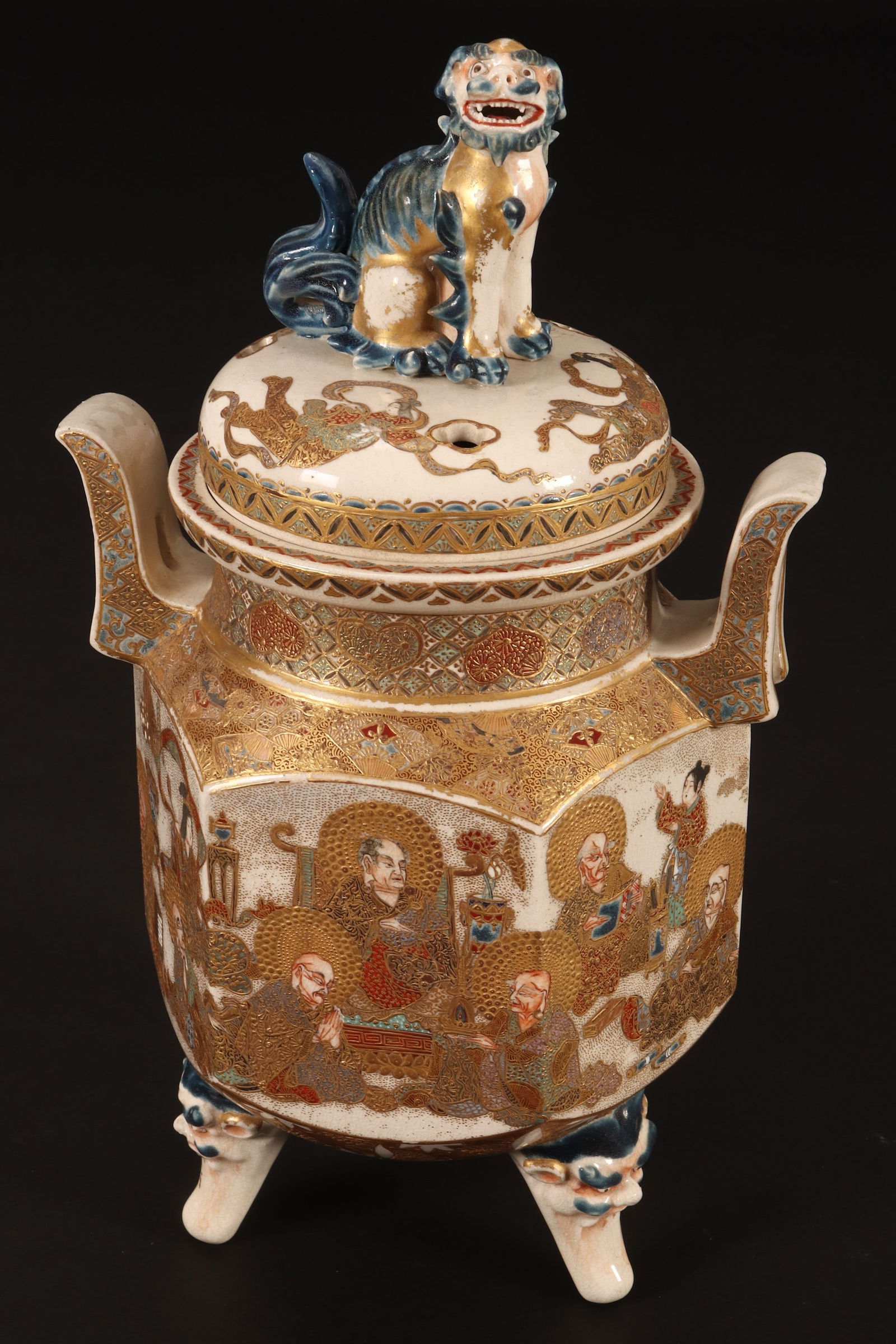 Large Satsuma Meiji Period Lidded Koro,: the slightly domed cover set with large shishi finial, raised upon a facetted body with twin handles, decorated with frieze of seated deities beneath gilt halos, with gilt and brocade accents, raised