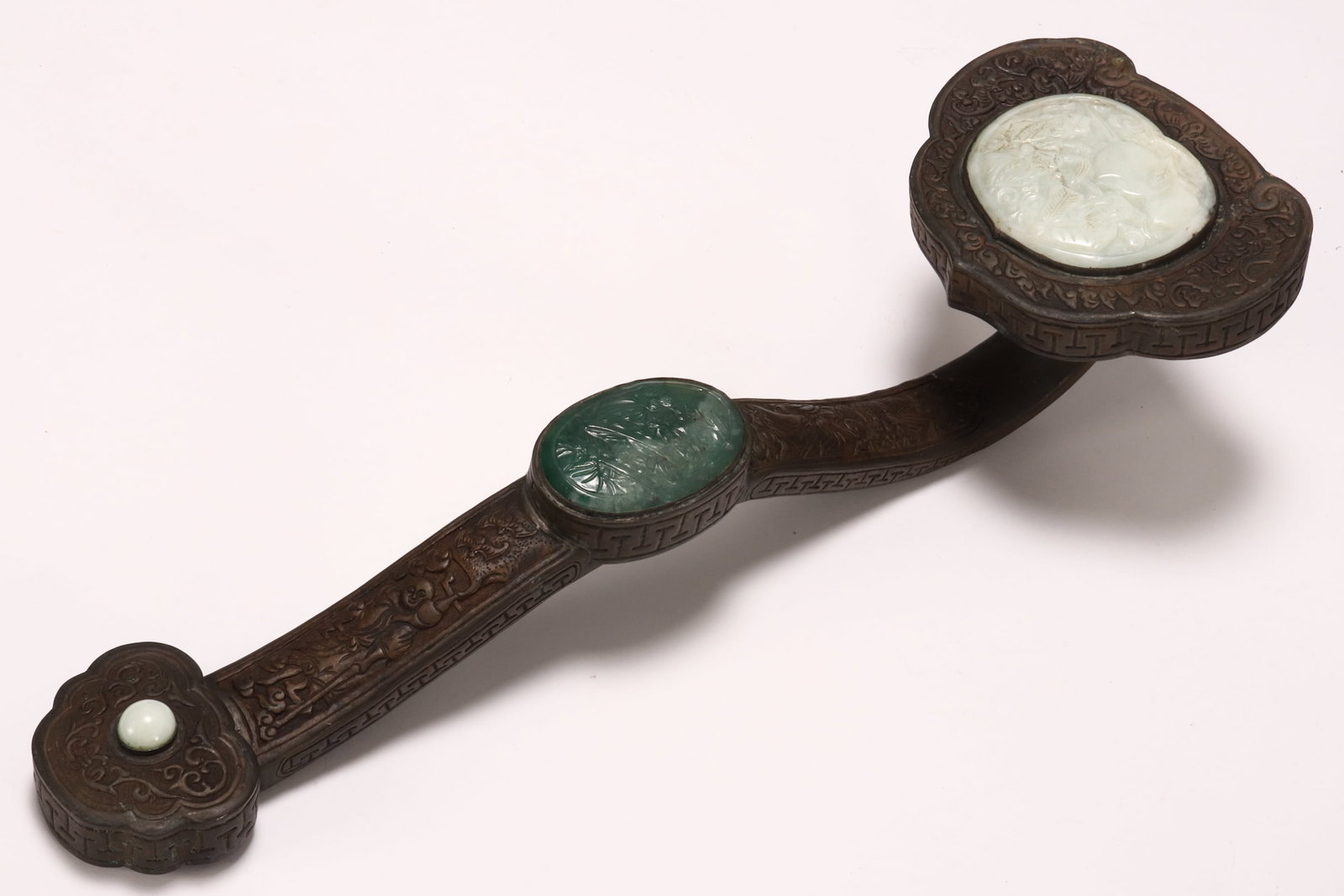 Large Chinese Jade and Copper Ruyi,: of conventional form, decorated with three jade plaques carved with figures, the frame embossed with bats and figures, length 48cm