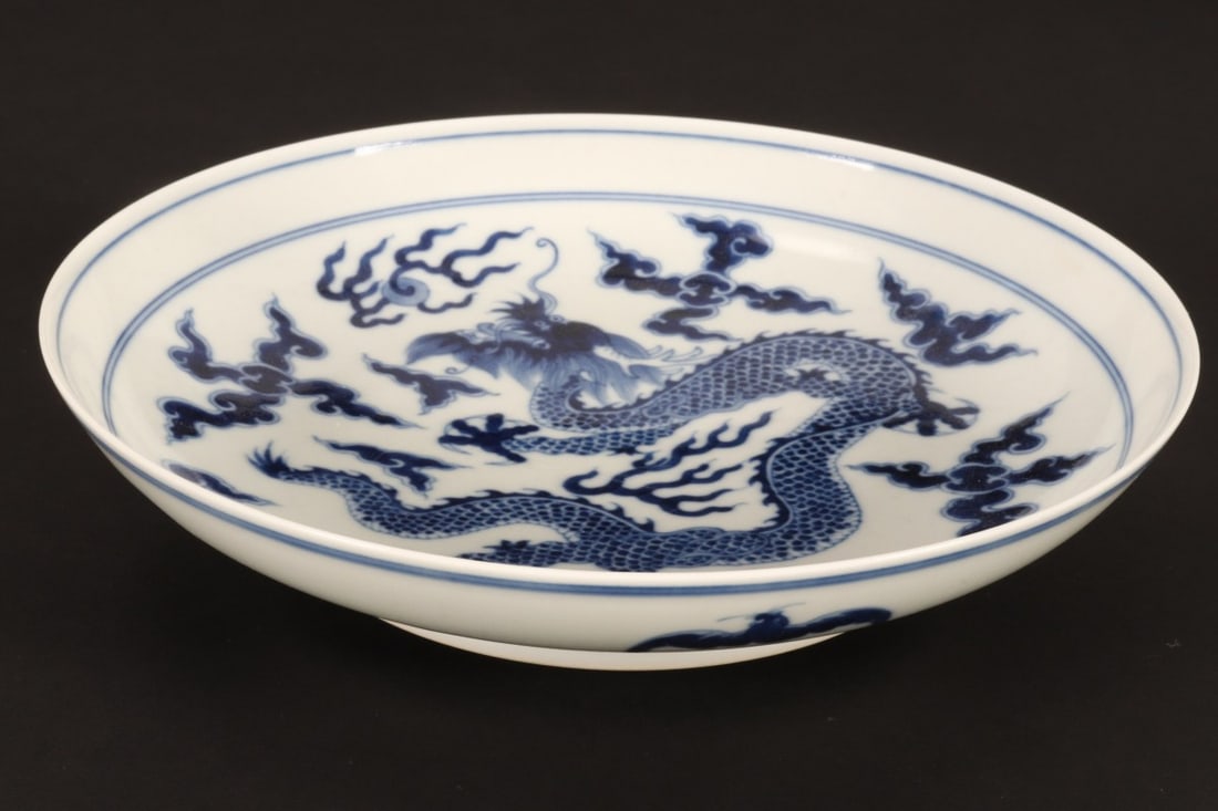 Chinese Blue and White Porcelain Bowl,: of shallow form, the well decorated with a central medallion containing a dragon in pursuit of the flaming pearl, above turbulent waves, the exterior decorated with five bats, six character mark to ba