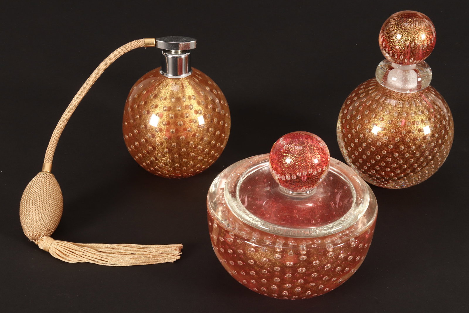 Rare Set of Three Archimede Seguso 'Bullicante' Dressing Table Items,: comprising atomiser, perfume bottle and jar and cover, of baluster form, in ruby and clear glass, accented with gilt fleck and air bubbles to the body, labels to base of two, height 15.5cm, 13cm and 1