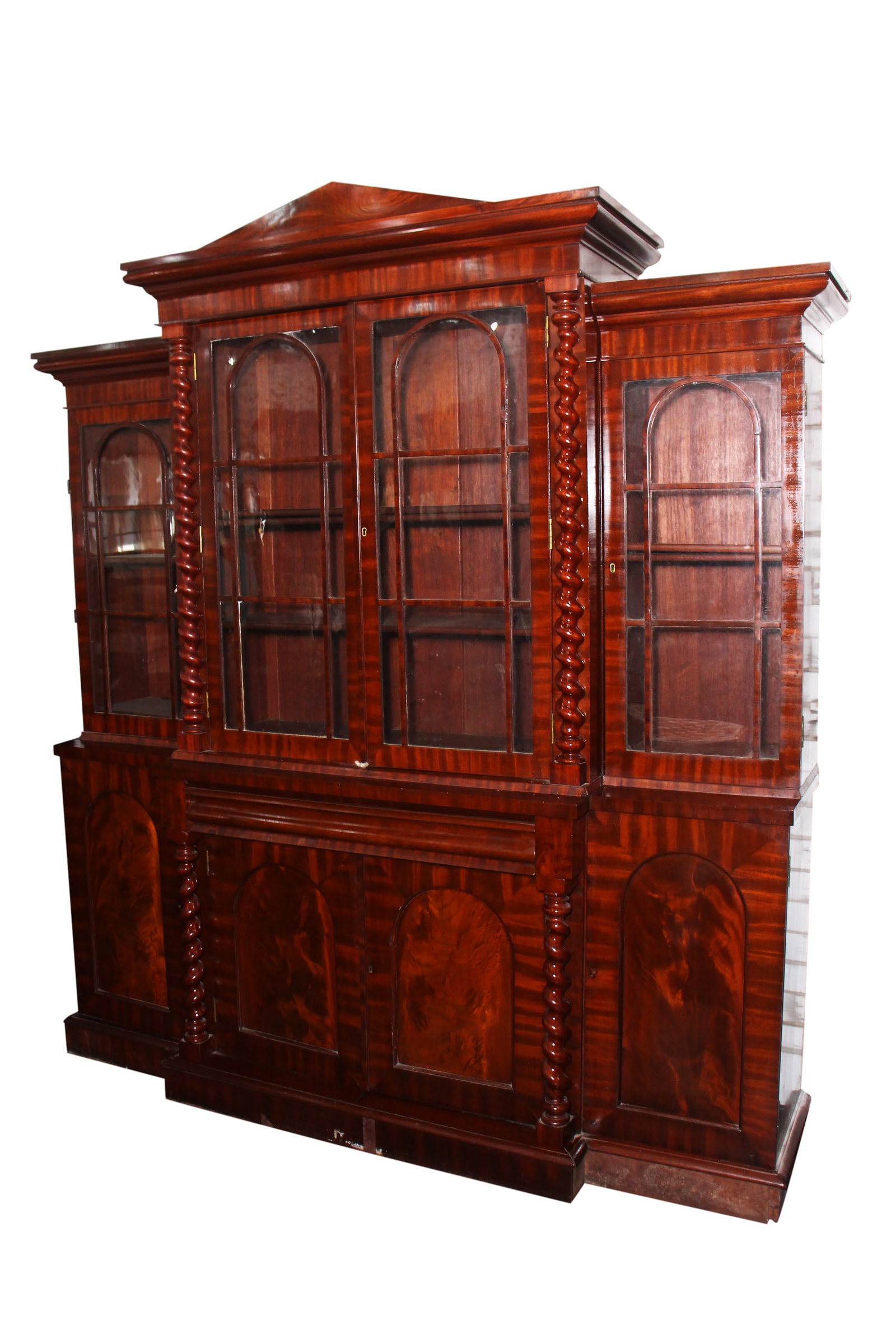 19th Century Australian Cedar Breakfront Bookcase,: with arched glazed display doors, with spiral column supports and pitch pediment, above arched panel doors below a single drawer, the whole on a bracket base, a/f (includes box contaning missing venee