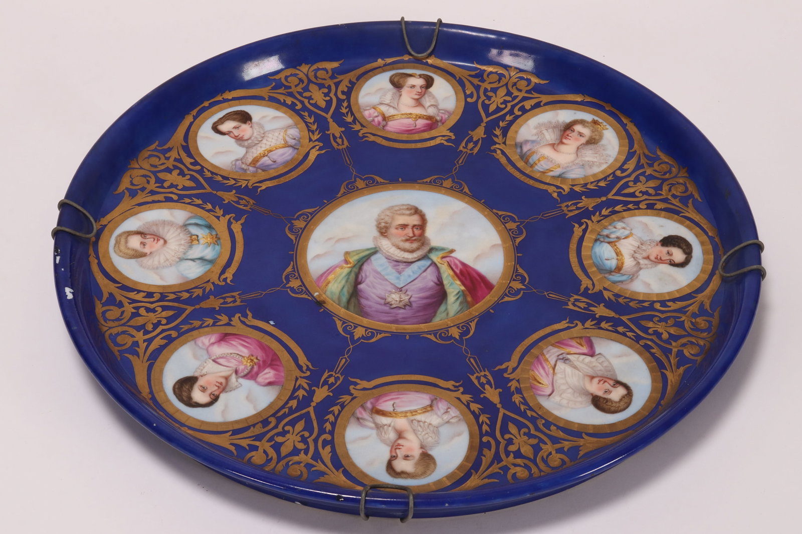 Large Limoges Porcelain Charger,: of handsome proportions, decorated with a central portrait of Henry IV, surrounded by eight roundel portraits of his wives, on a royal blue ground, a/f, titles inscribed verso, diameter 48.5cm