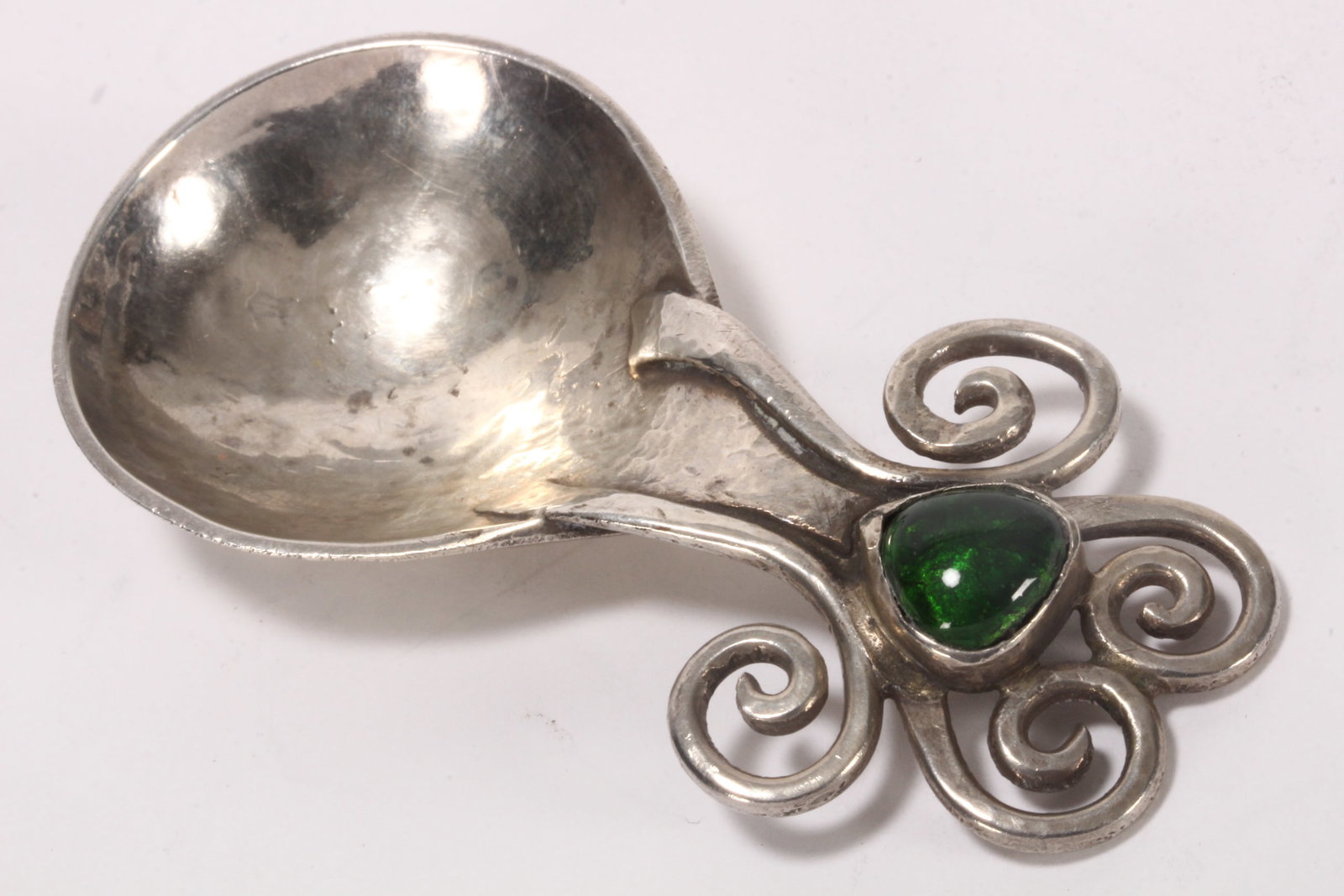 Rare Arts and Crafts Sterling Silver Caddy Spoon,: hallmarked London, 1905, R.N & C.R (Omar Ramsden & Alwyn Carr), set with central green enamel cabochon, surrounded by four scrolls, above a deep bowl, in hand beaten finish, total weight 35g, length 8