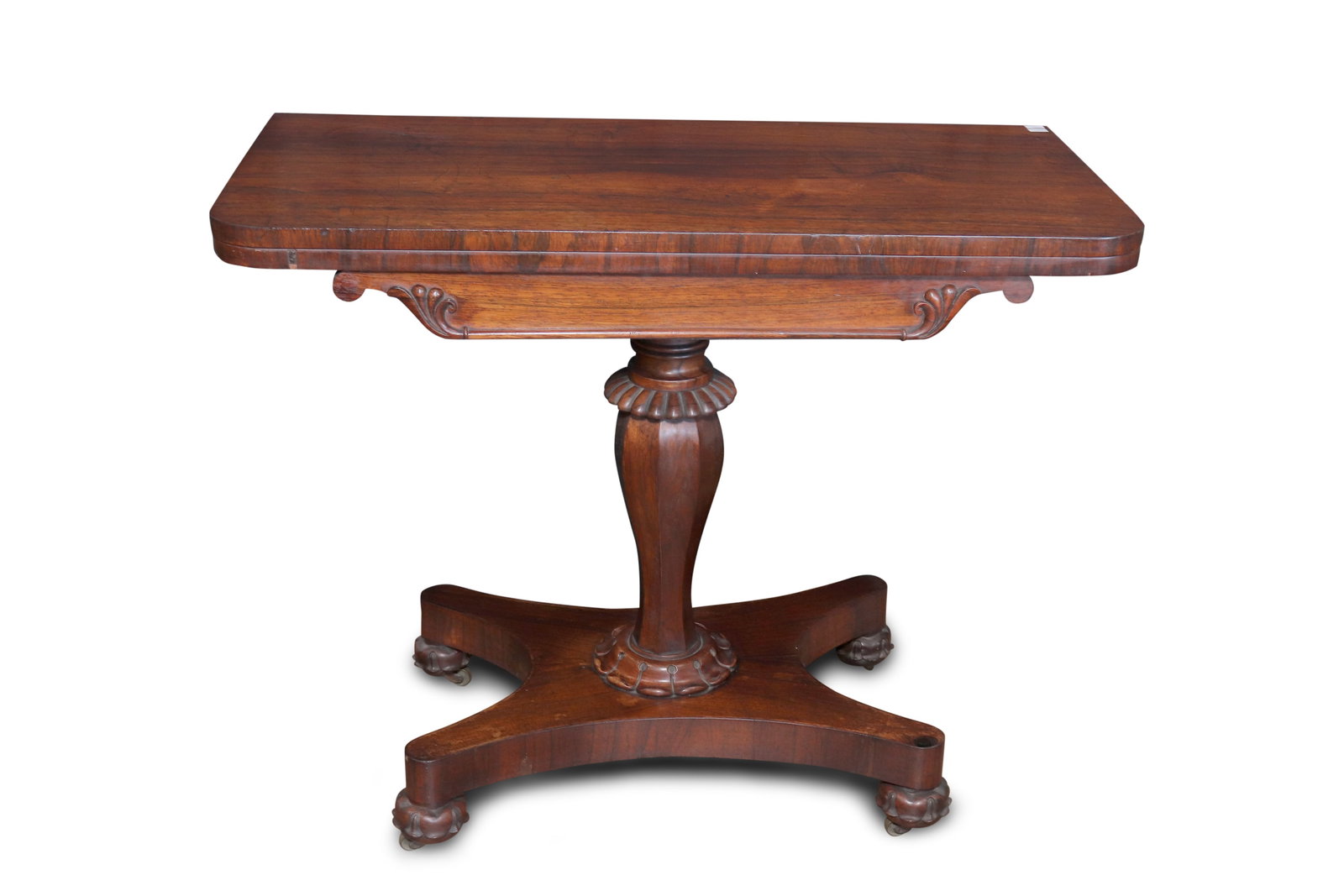 William IV Rosewood Card Table,: the rectangular foldover top with green felt underside, supported above a faceted baluster pedestal, on a quatrefoil base with casters, height 74cm x width 91.5cm x depth 45cm