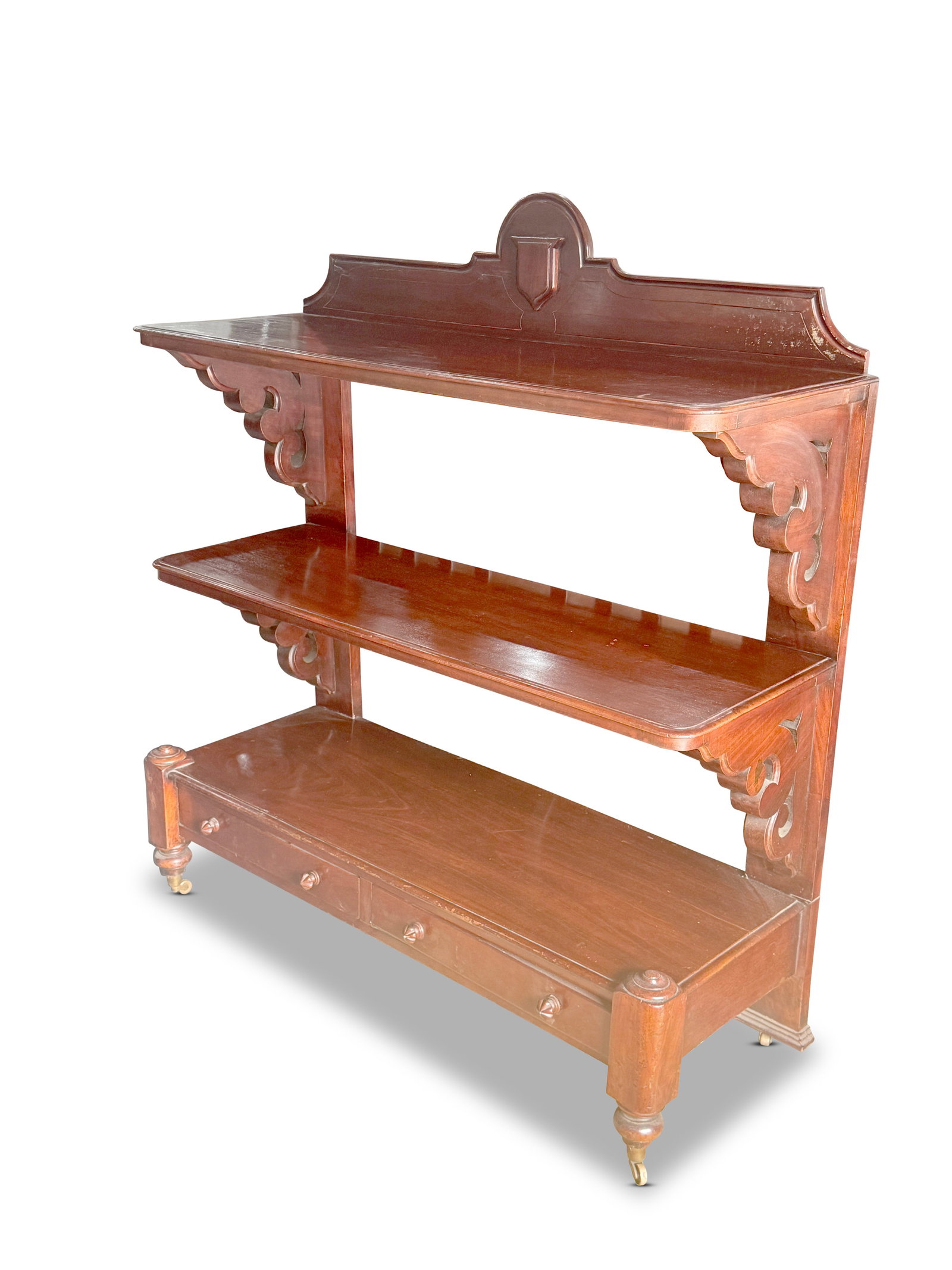 Victorian Mahogany Three Tier Dumb Waiter,: of rectangular form, with a medallion crest rail, above three shelves with carved bracket supports, the lower section with drawers, on turned legs on casters, 136cm x 121cm x 42cm
