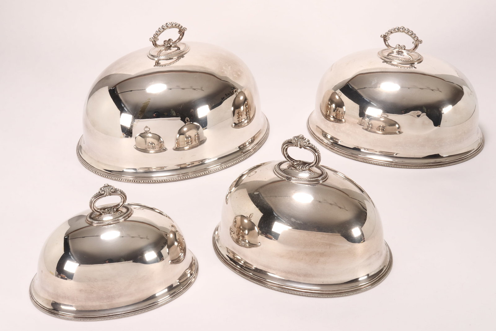 Four Edwardian Graduated Silver Plate Cloches,: the larger two by Harrison Brothers & Howson, height 25cm (including handle) x length 40.5cm and height 22cm (including handle) x length 36cm, the smaller two measuring height 21cm (including handle) 
