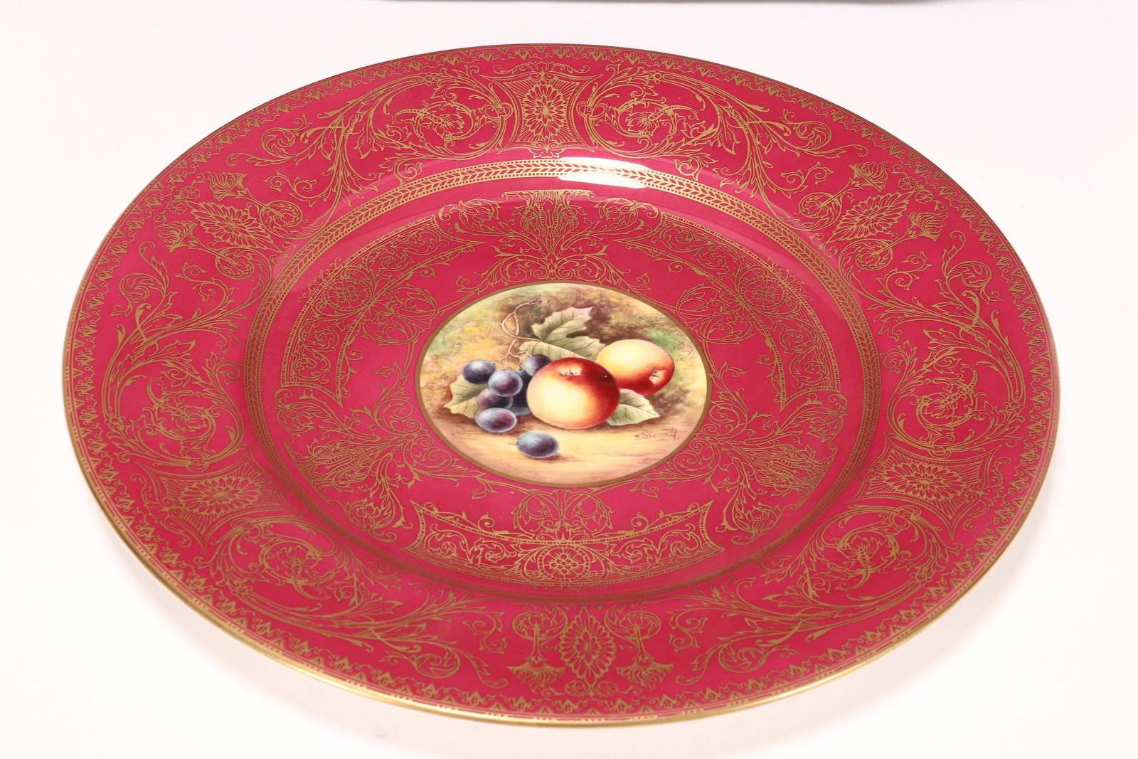Royal Worcester Porcelain Cabinet Plate,: of circular form, decorated with central roundel hand painted with a still life, signed J.Skenett, surrounded by scrolling foliage and flowers, in tones of maroon, green, blue and orange, with gilt ac