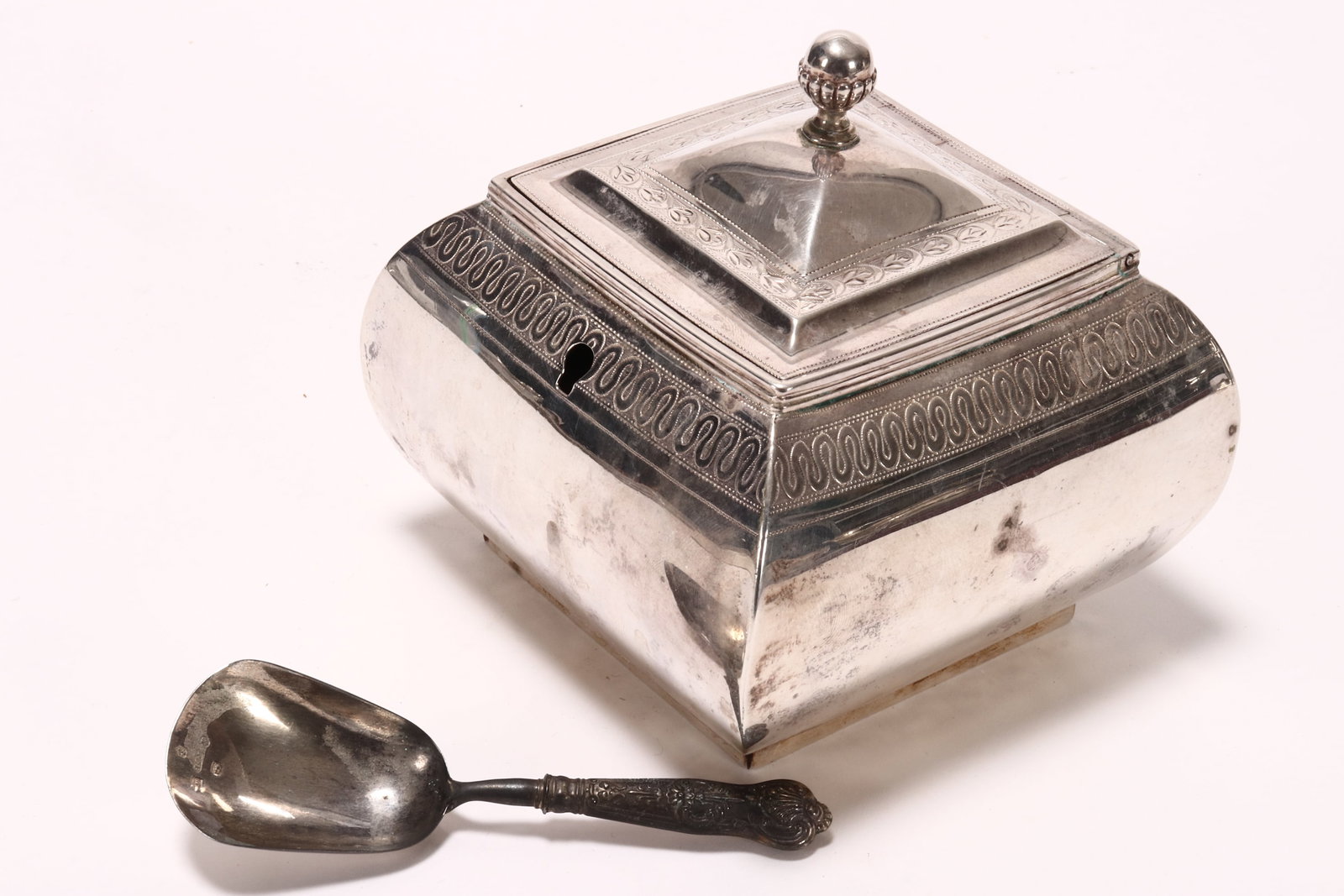 George III Sterling Silver Tea Caddy,: hallmarked London, 1803, R.H//S.H (Robert Hennell I & Samuel Hennell), the hinged cover set with acorn finial, above a facetted bun shaped body, decorated with bright cut borders, together with a matc