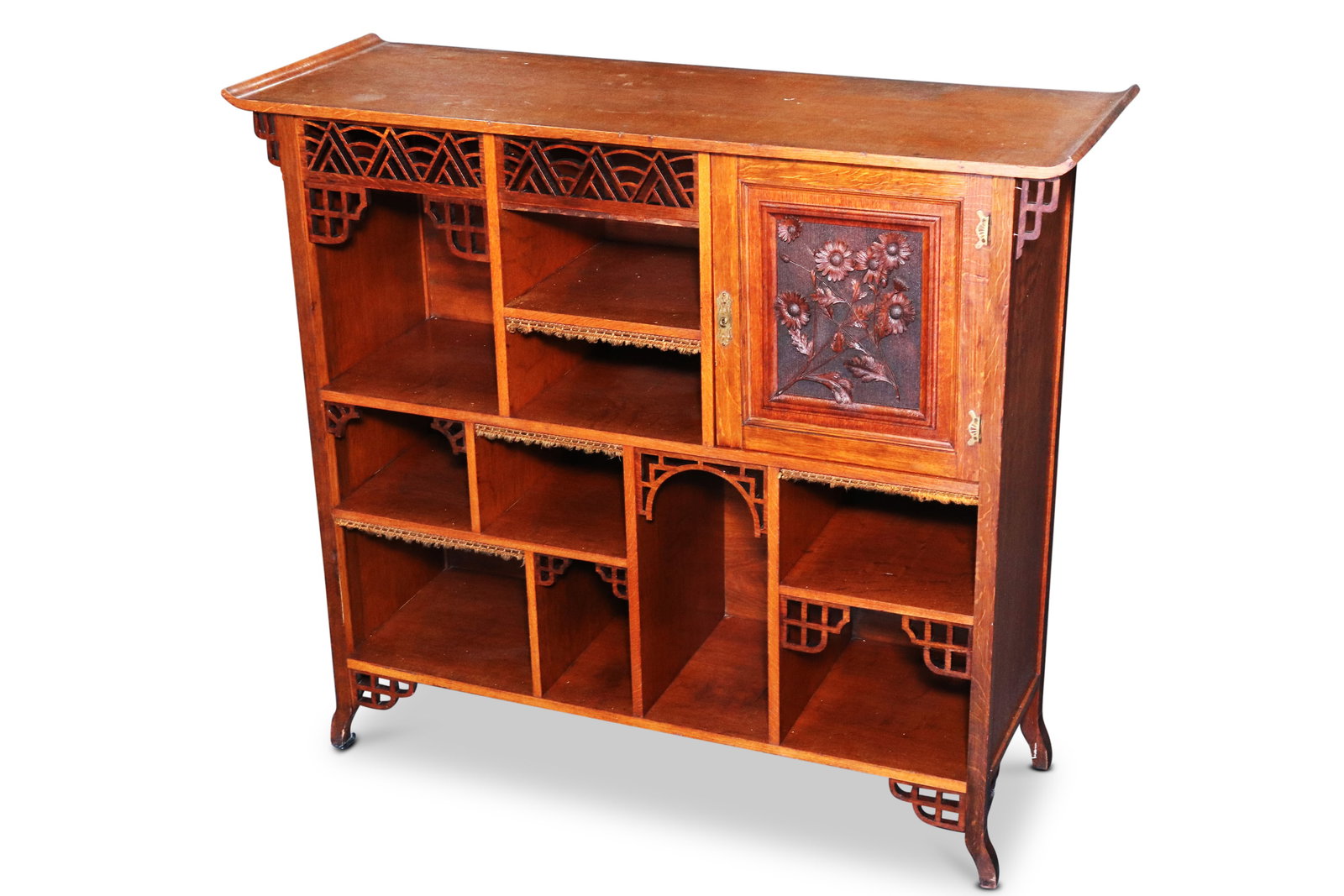Anglo-Japanese Quartered Sun-Ray Oak Cabinet,: in stained oak, the top with upturned edges above asymmetrical shelves with reticulated aprons, the single cabinet door with carved sunken relief of daisies enclosing two shelves, raised on four shape