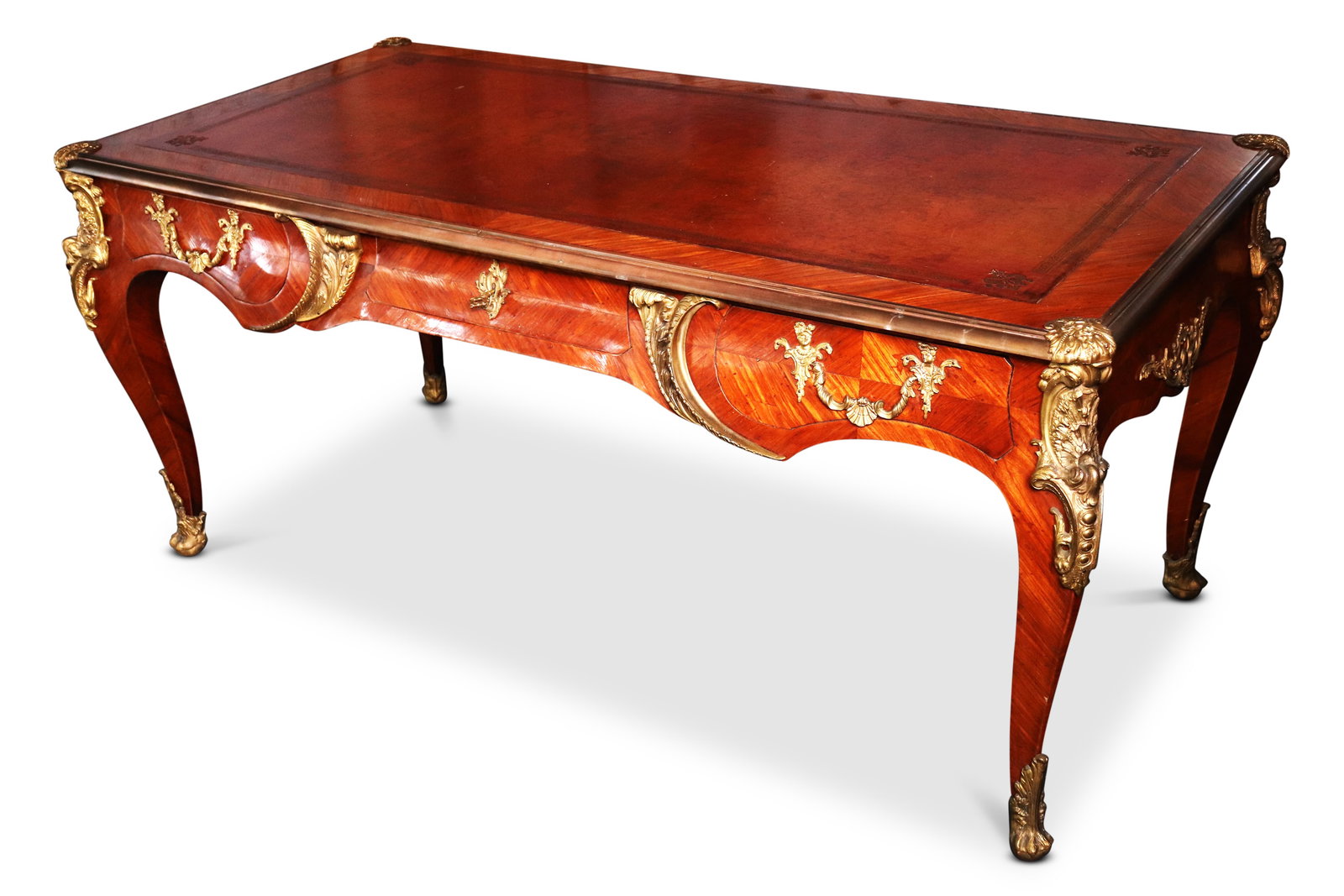 Stunning 19th Century French Bureau Plat,: in Louis XV taste, of handsome proportions, with inset tooled leather top with herringbone king wood veneer, set with three drawers, all beautifully accented with ormolu mounts, flanked by four cabrio