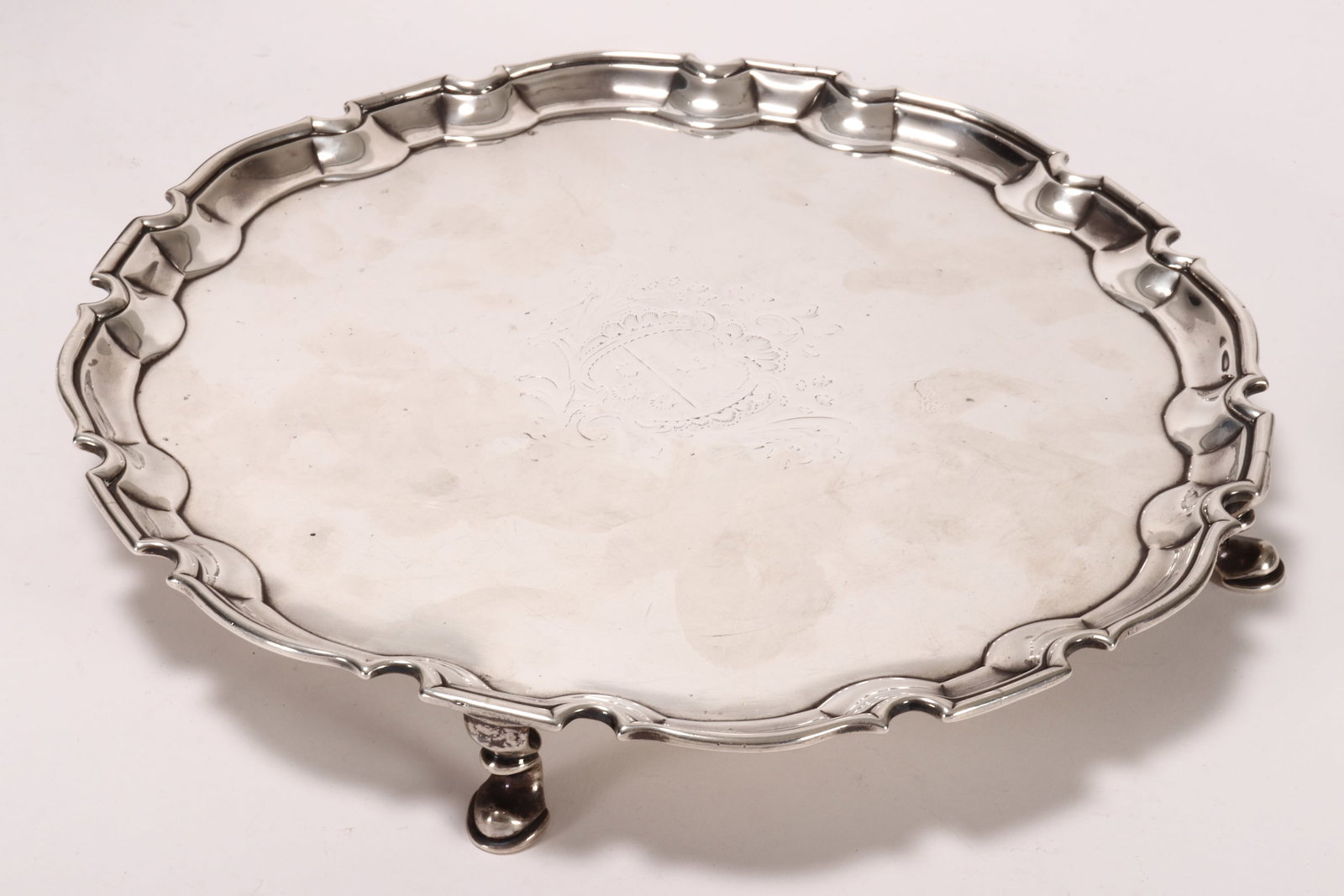 George II Sterling Silver Footed Salver,: hallmarked London, 1734, R.A (Robert Abercromby), with a piecrust border, decorated with central armorial, raised on four hoof feet, total weight 680g, diameter 26cm