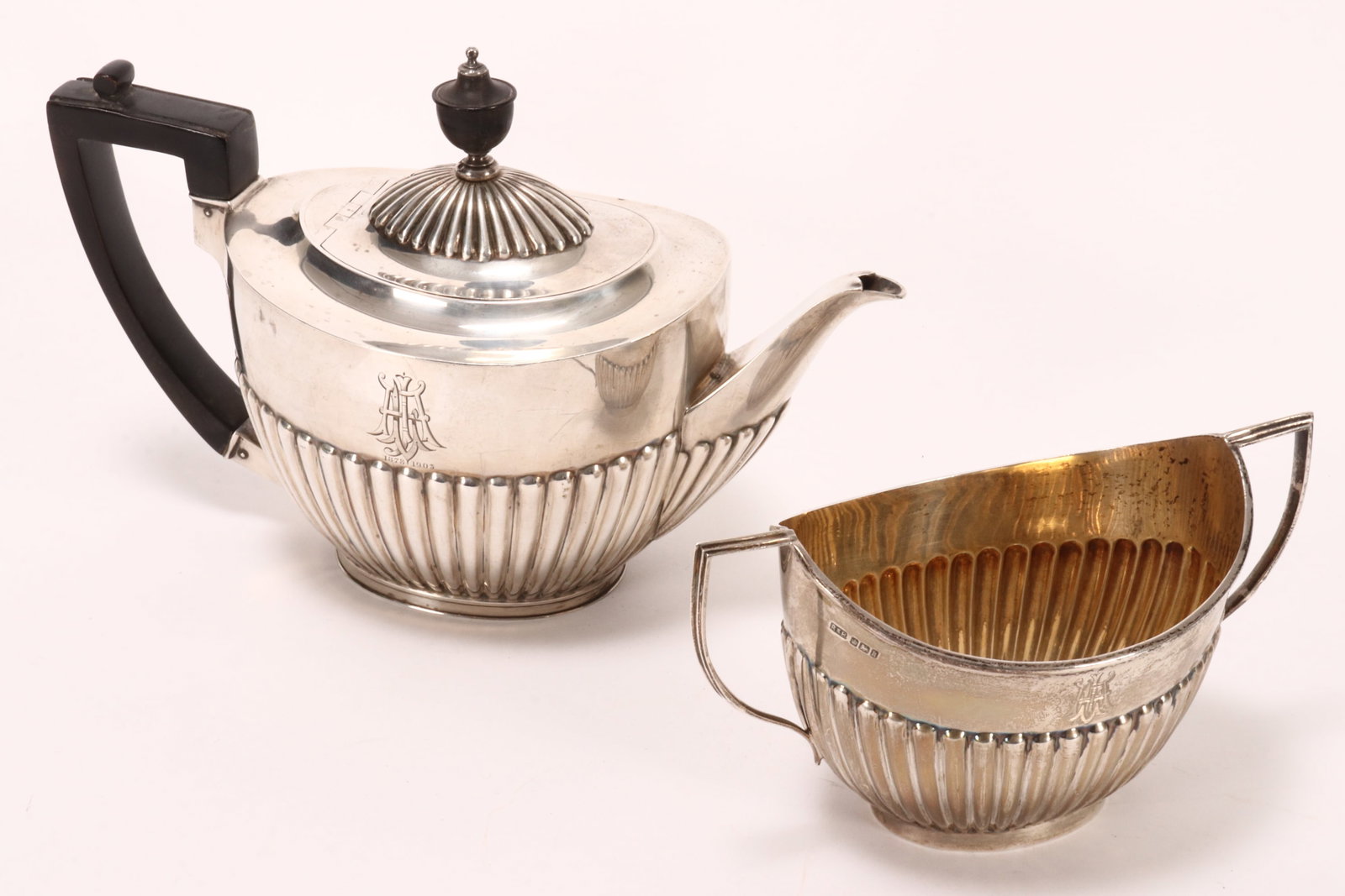 Edwardian Sterling Silver Teapot and Sugar Bowl,: hallmarked Sheffield, 1902, R&B (Roberts & Belk), of elliptical form with a lobed lower body, decorated with incised monogram to body, raised on an oval base, total weight 818g, height 17cm and 9.5cm 