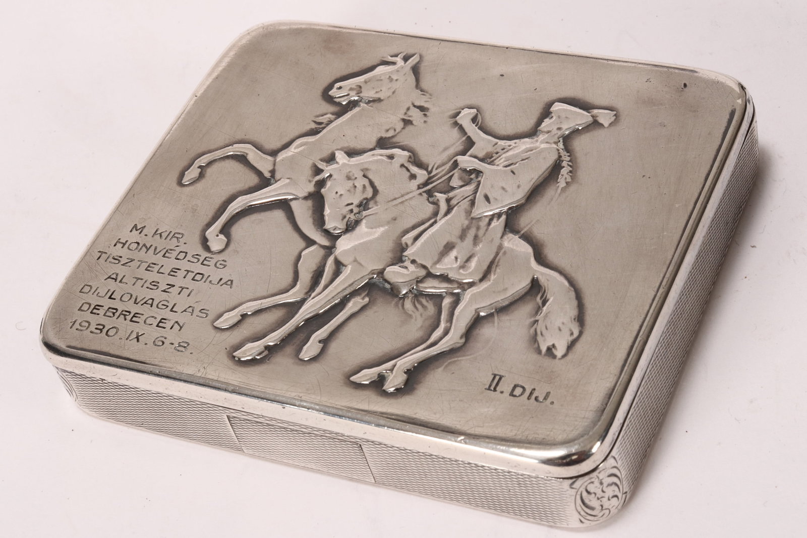 19th Century Austro-Hungarian Silver Cigarette Box: marked 900, of rectangular form, the hinged cover embossed with figure on horseback, with inscription lower left and engine turned decoration to sides and base, opening to a gilt interior, total weigh