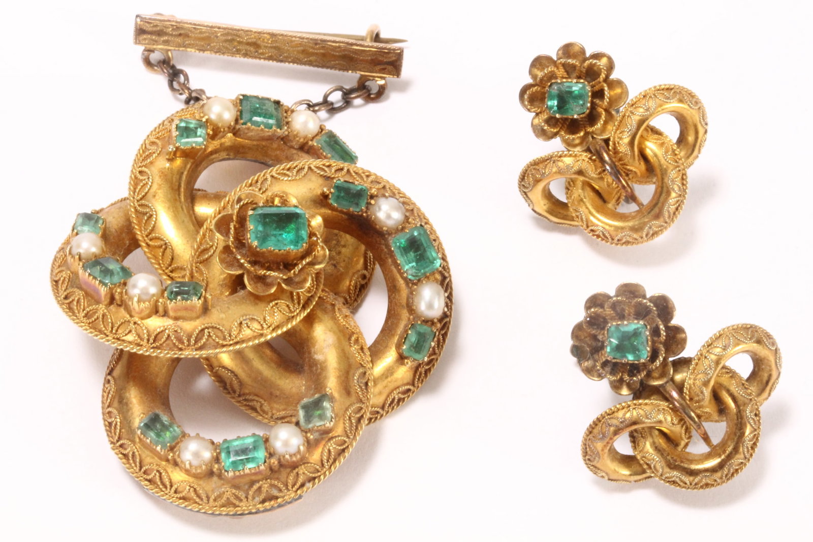 Victorian 15ct Gold, Emerald & Seed Pearl Suite,: comprising a brooch and pair of earrings, the brooch stamped 15, of pierced interlocked ring form, each ring with rope twist and filigree border and decorated with emeralds and seed pearls, totaling t