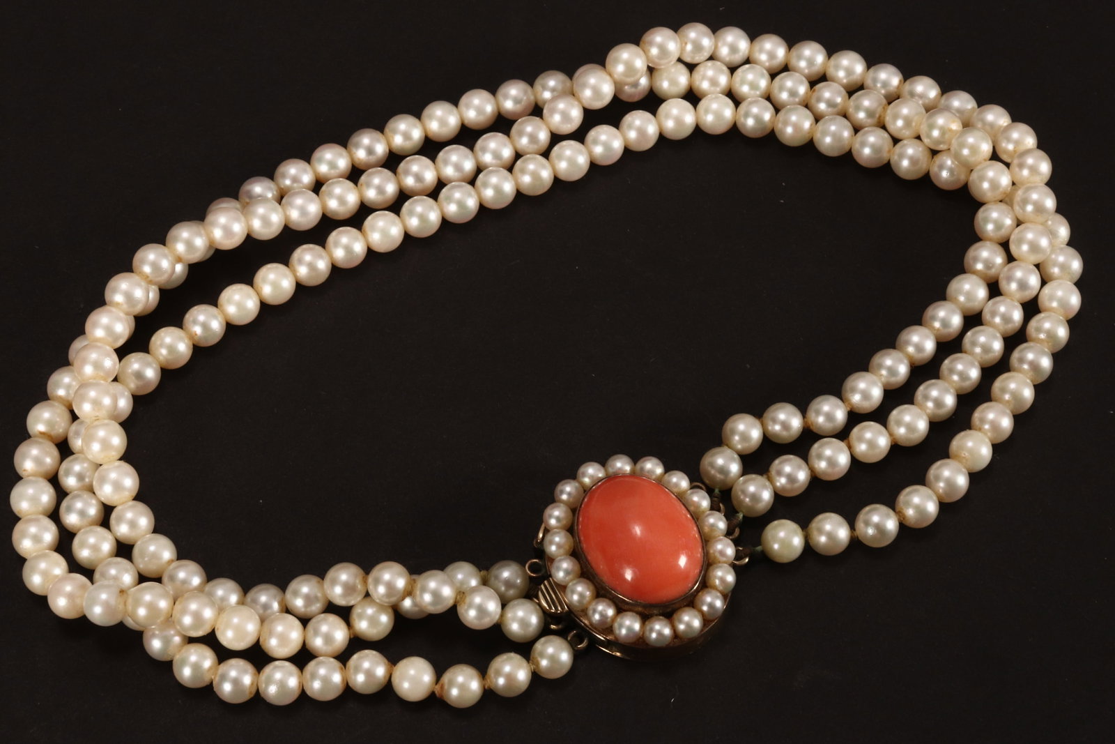 Triple-Strand Pearl Choker with 9ct Gold Clasp,: the pearls of uniform spherical form, diameter 5mm, the clasp accented with coral cabochon, a/f (missing one strand), length 365mm