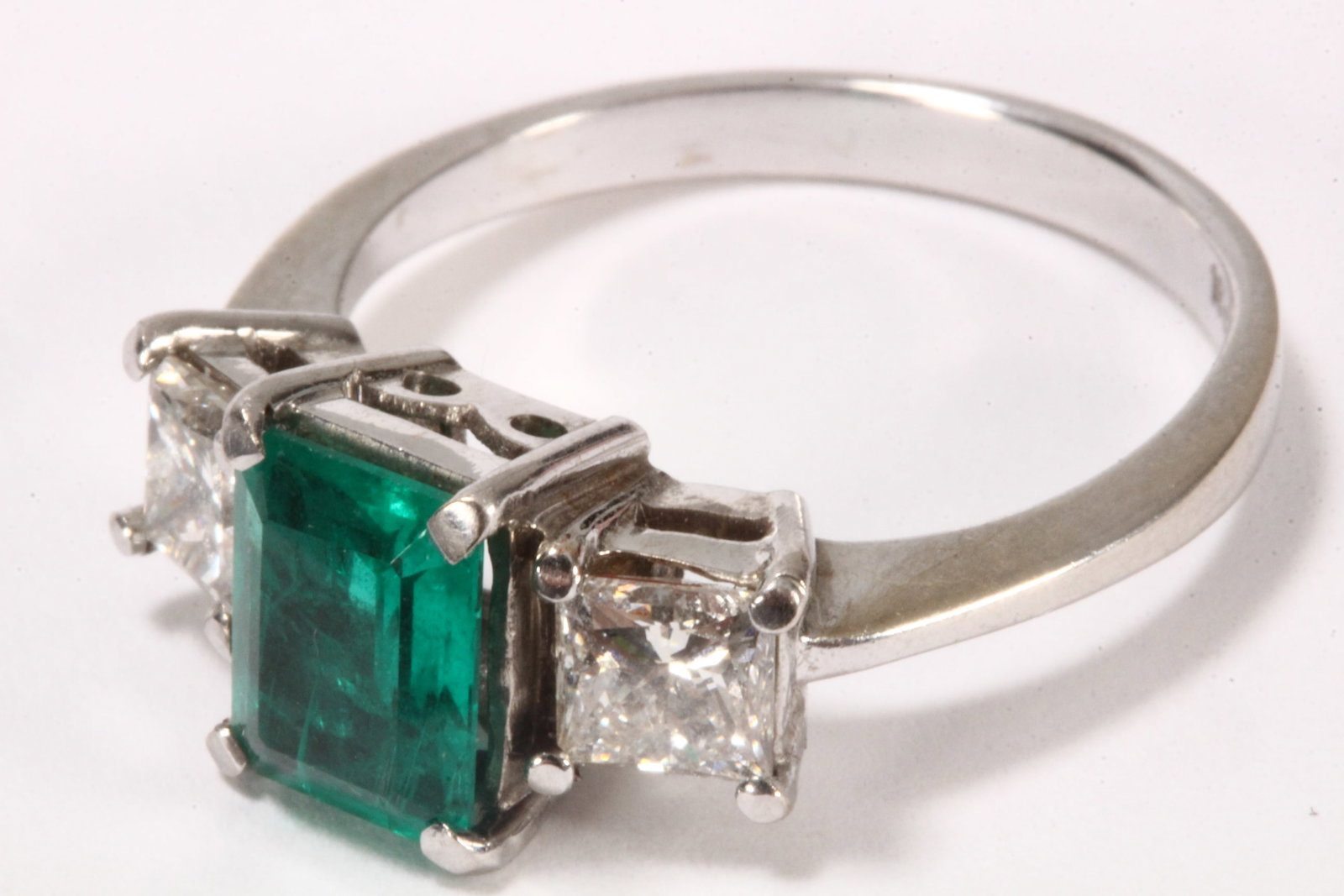 18ct White Gold Emerald & Diamond Trinity Ring,: stamped 18ct, with central emerald cut emerald of approx. 1.00ct, flanked by two princess cut diamonds of approx. 0.50ct each, total weight 4.9g, size P Provenance: Bonhams Sydney, Jewellery, sale 200