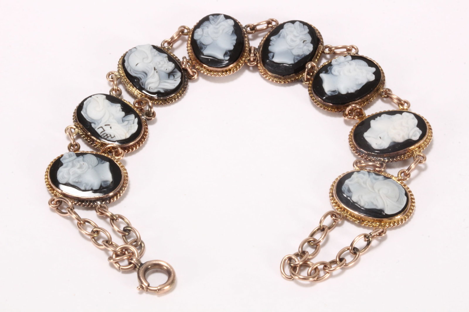Nice 9ct Gold Cameo Bracelet,: stamped 9ct, featuring eight oval black and white cameo panels, depicting men and women in profile, set within gold rope twist frames united by fine chain links, uniting via a spring ring clasp, total